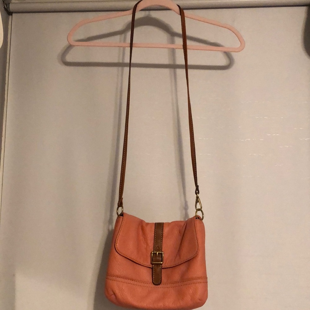 A peach colored cross body Fossil purse.